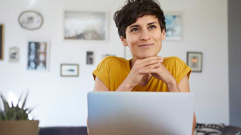 Woman sitting down with laptop in front of her, smiling