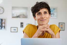 Woman sitting down with laptop in front of her, smiling