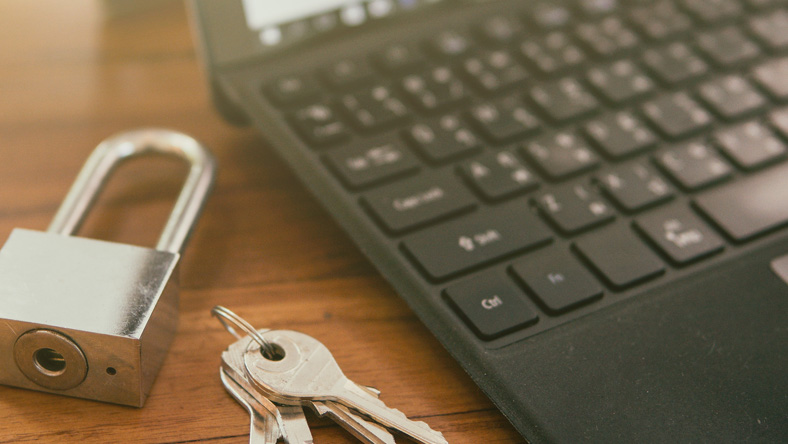 Keypad and keys resting next to laptop on table