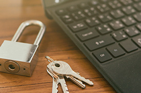 Keypad and keys resting next to laptop on table