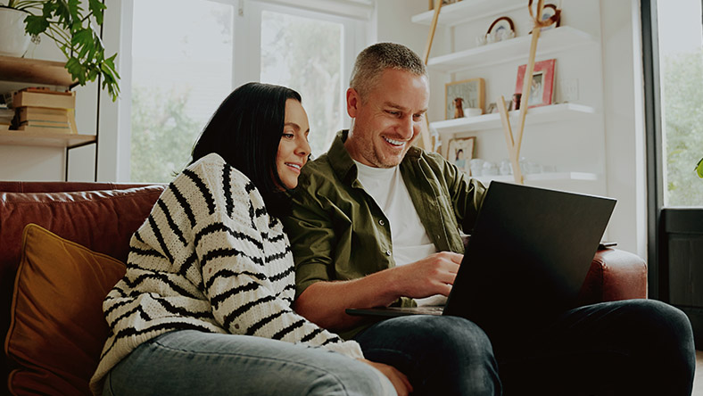 Man sitting on couch holding a tablet and smiling