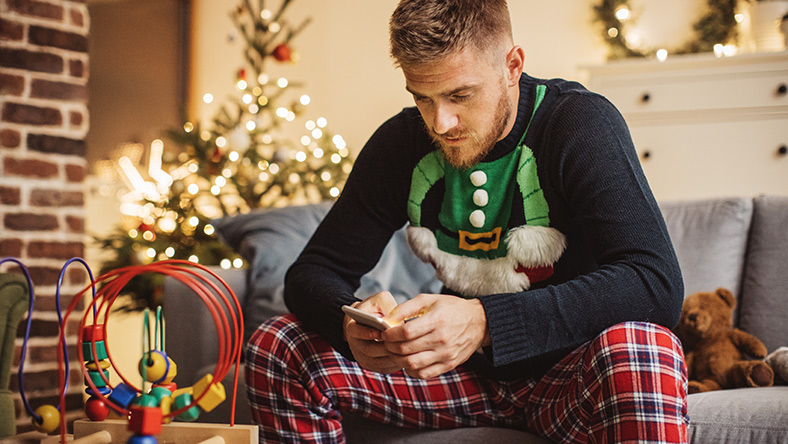 Man in Christmas themed outfit on mobile phone at home