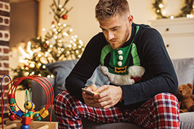 Man in Christmas themed outfit on mobile phone at home