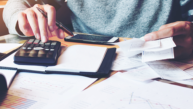 A person using a calculator, cropped to show just the calculator, hands and torso.