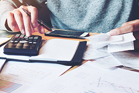 A person using a calculator, cropped to show just the calculator, hands and torso.