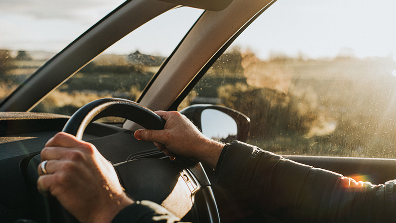 A pair of hands grip the steering wheel of a new car.