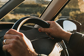 A pair of hands grip the steering wheel of a new car.