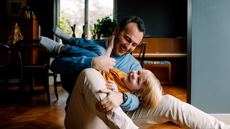 Smiling man sitting in chair while holding smiling child