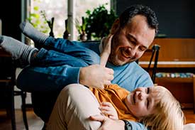 Smiling man sitting in chair while holding smiling child