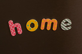 Four alphabetical fridge magnets spell home on the door of a kitchen fridge.