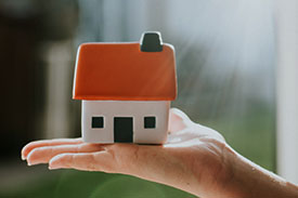 A tiny house sits in the palm of someone's hand.