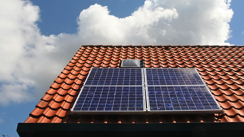 A rooftop with a grid of solar panels on a sunny day.