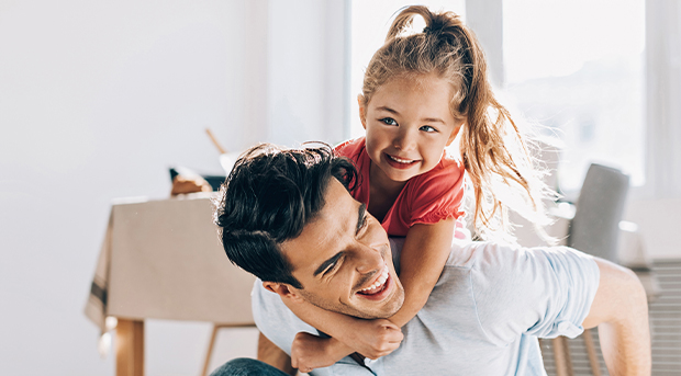 A dad plays with his daughter on the floor of their family home.