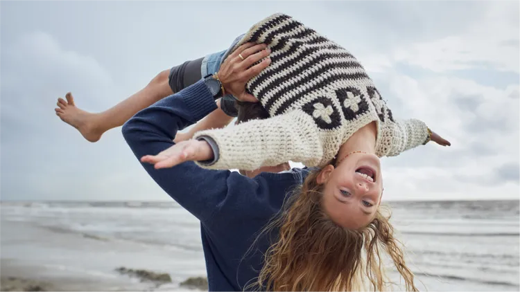 A child and their relative have fun at the beach.