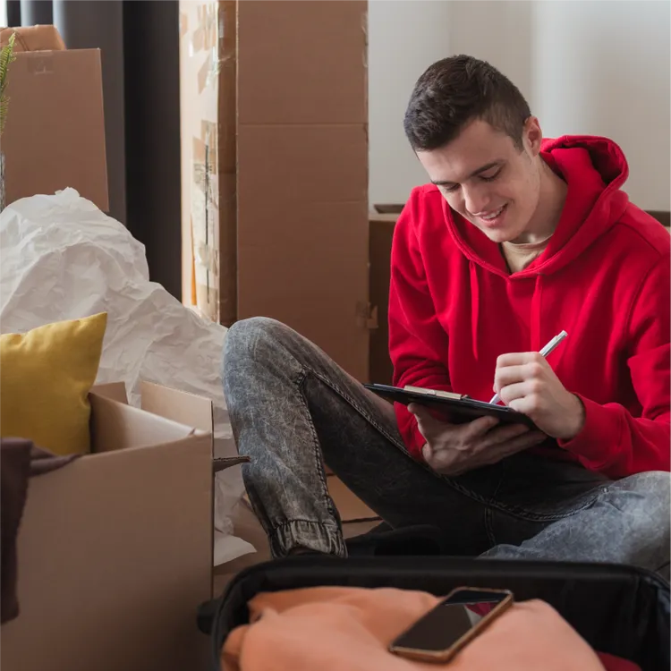 A young man checks some cardboard boxes in his new living room.